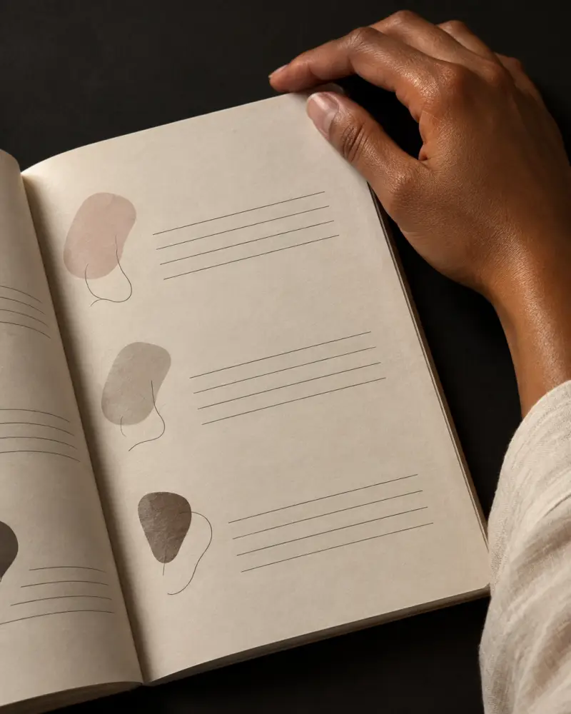 Grayscale editorial detail of a hand beside a monochrome black-and-white blueprint spread with a gold crown accent